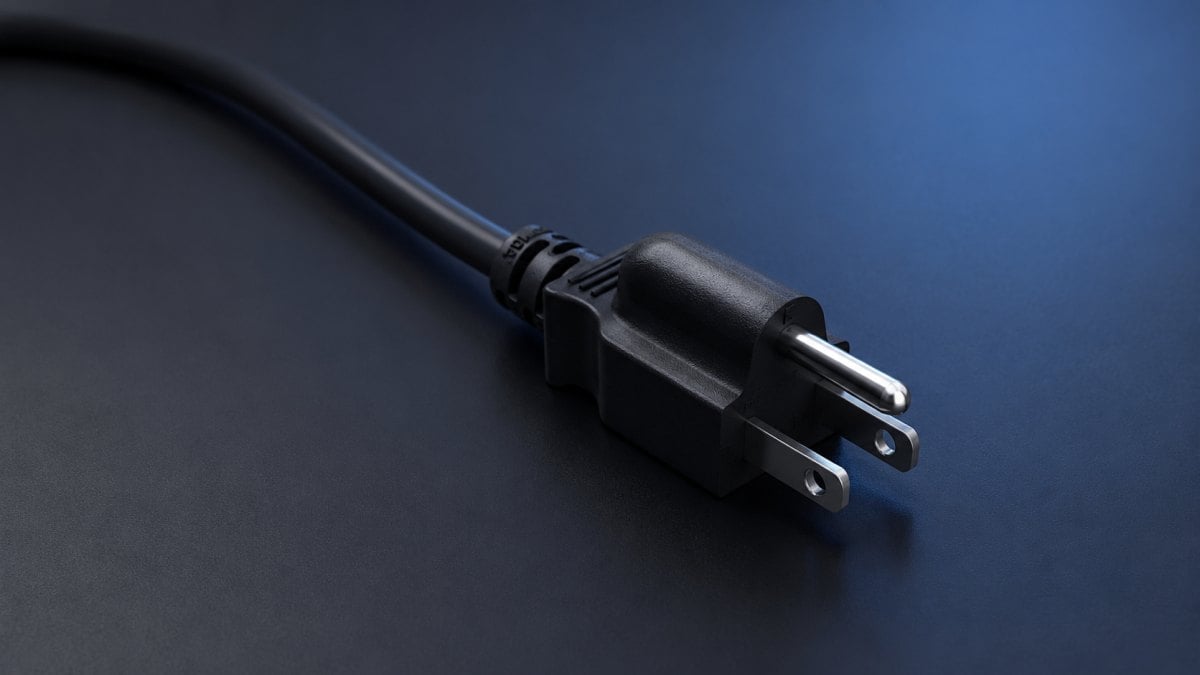 NEMA 5-15P three-prong power plug with narrow hot blade, wide neutral blade, and U-shaped ground pin on a clean studio background